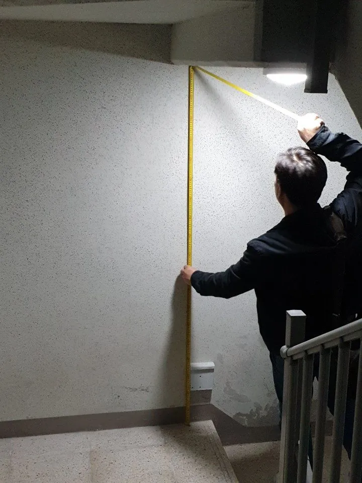 계단참 바닥에서 위쪽 보 아랫면까지 줄자로 높이를 재는 모습